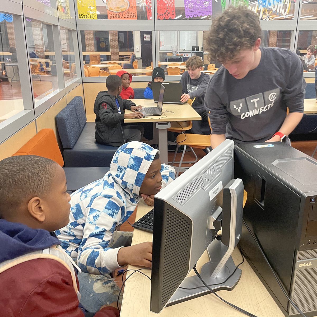 YTC member teaching younger students at a computer